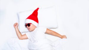 Baby runner with a santa hat and sunglasses resting in a bed