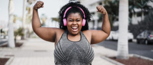 A plus-size Black woman in athletic clothes celebrates post-run. Am I a runner? Yes, you are!