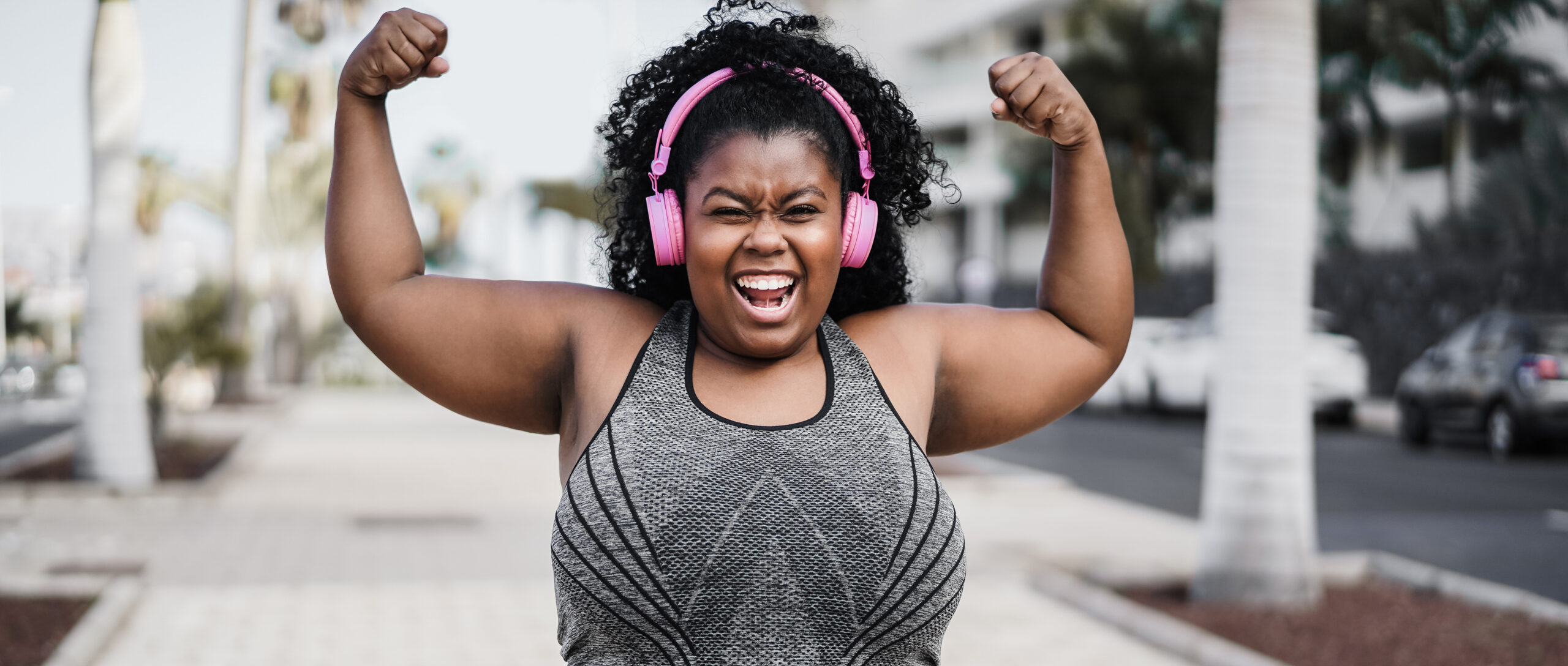 A plus-size Black woman in athletic clothes celebrates post-run. Am I a runner? Yes, you are!