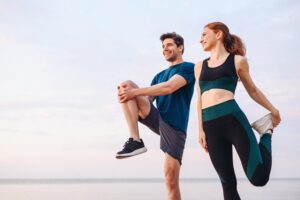 A young couple in athletic wear is stretching during their warm-up for a run