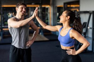 A young man and woman high-five in a gym