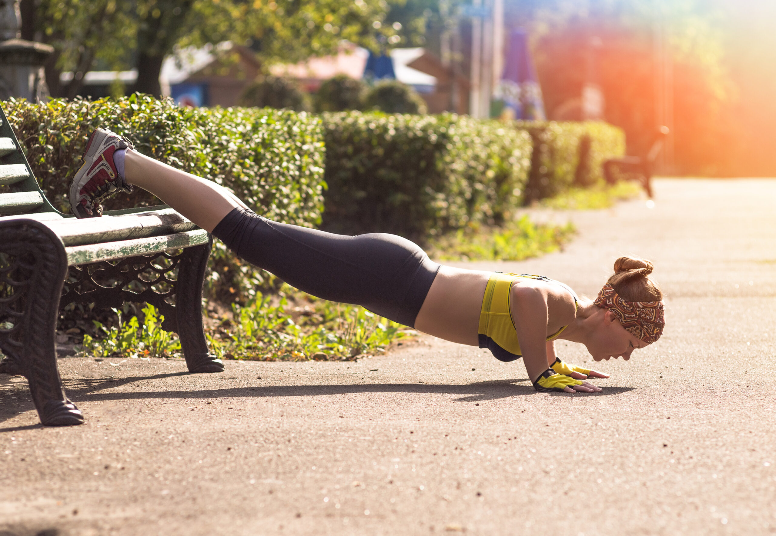 A young woman runner does cross-training during her run, pushups