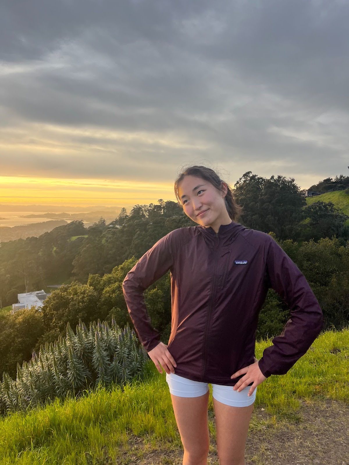 Chloe, President of Cal Running Club, standing by a railing with the ocean in the background