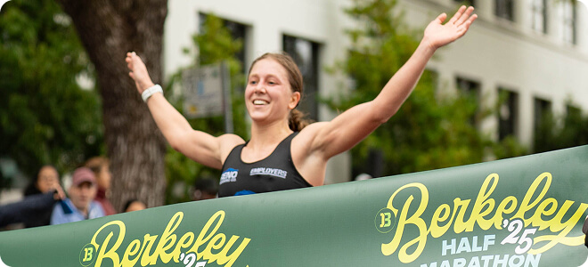 Runner with arms raised running across the finish line
